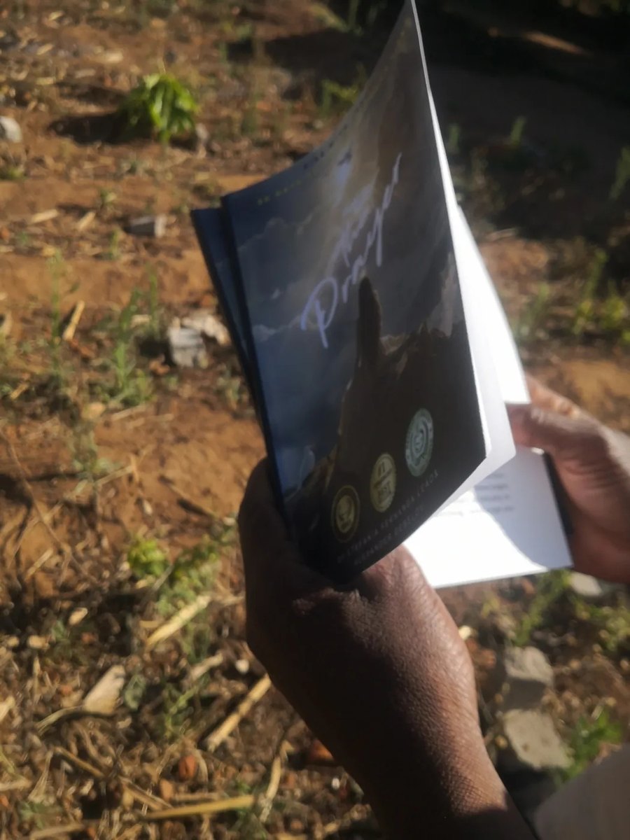 A reader in Malawi holding a physical copy of The Prayer