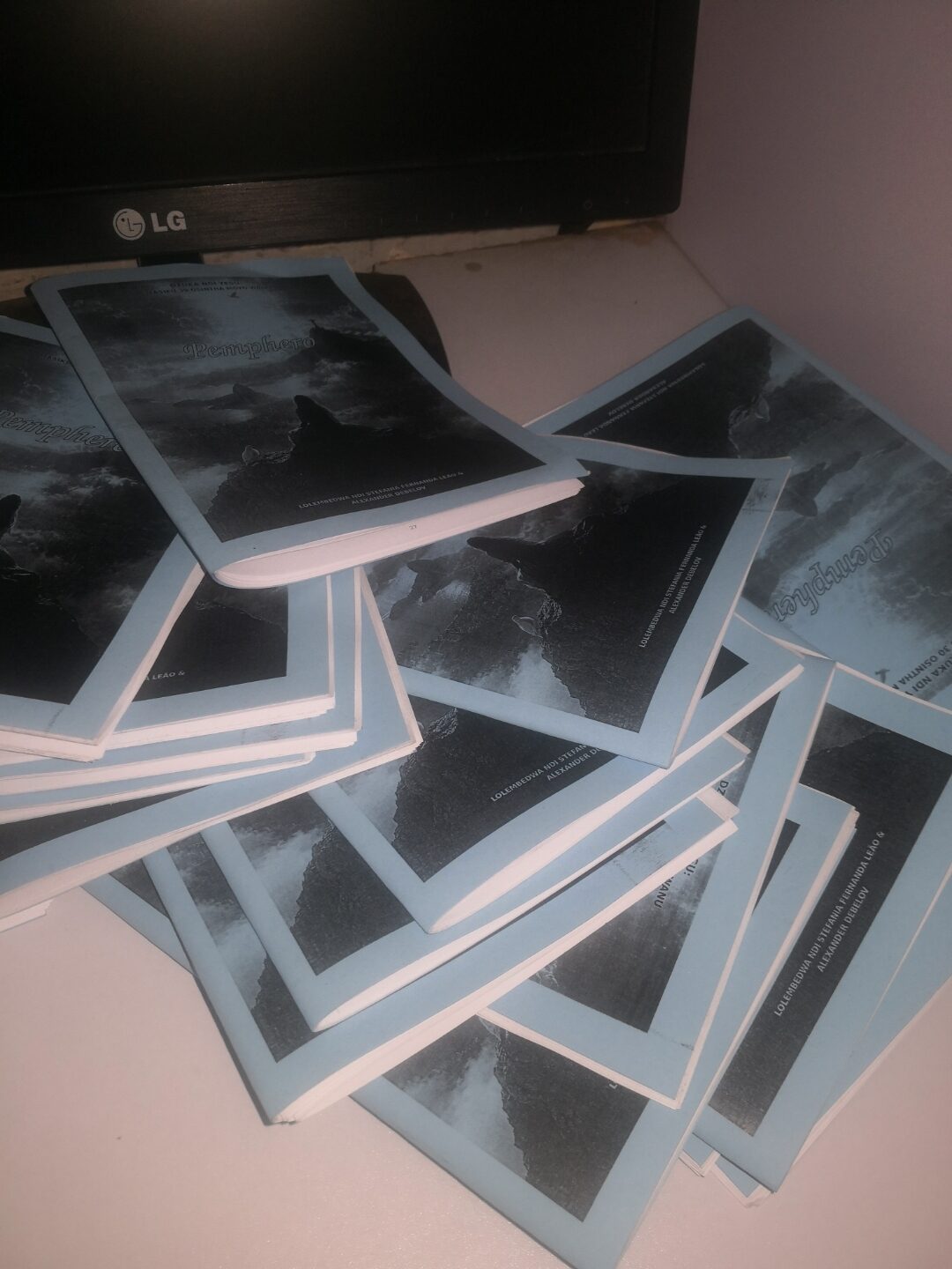 A stack of freshly printed copies of Pemphero, the Chichewa edition of The Prayer, fanned out on a desk